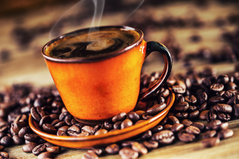 一杯冒着热气的咖啡与咖啡豆