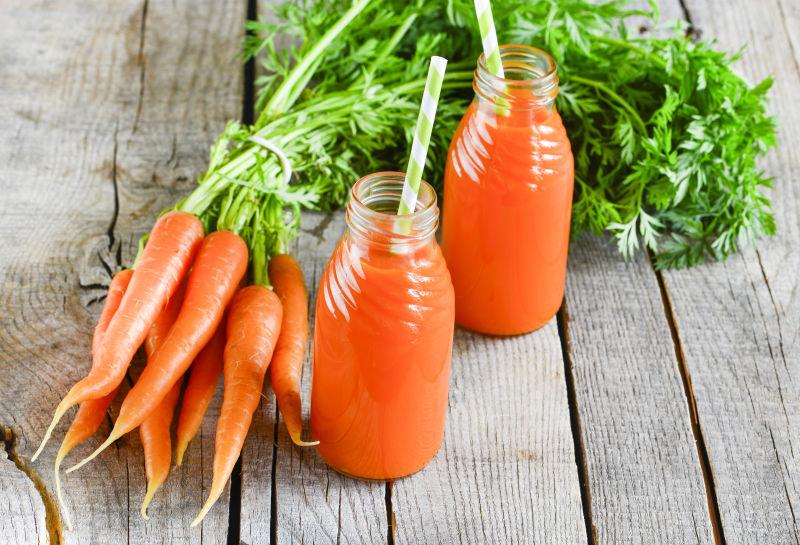 玻璃瓶里的胡萝卜汁和新鲜胡萝卜