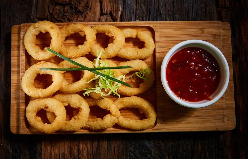 砧板上美味的炸鱿鱼圈和番茄酱