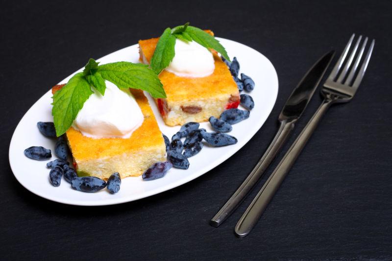 黑色桌上的可口浆果奶酪蛋糕和叉子