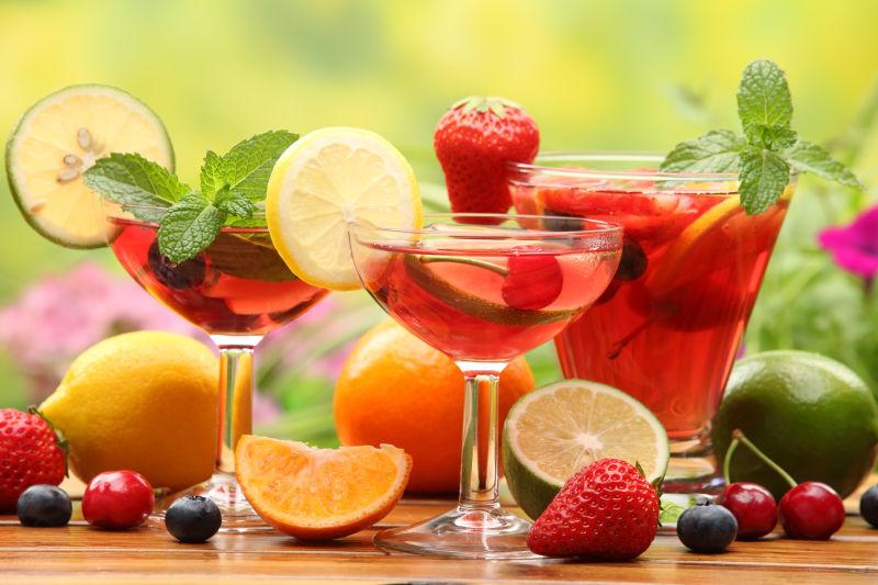 绿色背景下木桌上的一些水果和水果鸡尾酒