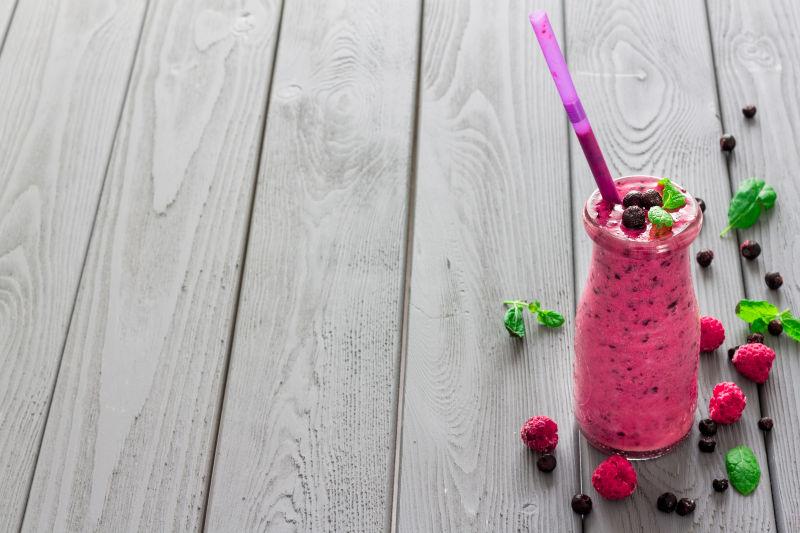 灰白色木桌上的草莓与蓝莓和覆盆子冰沙