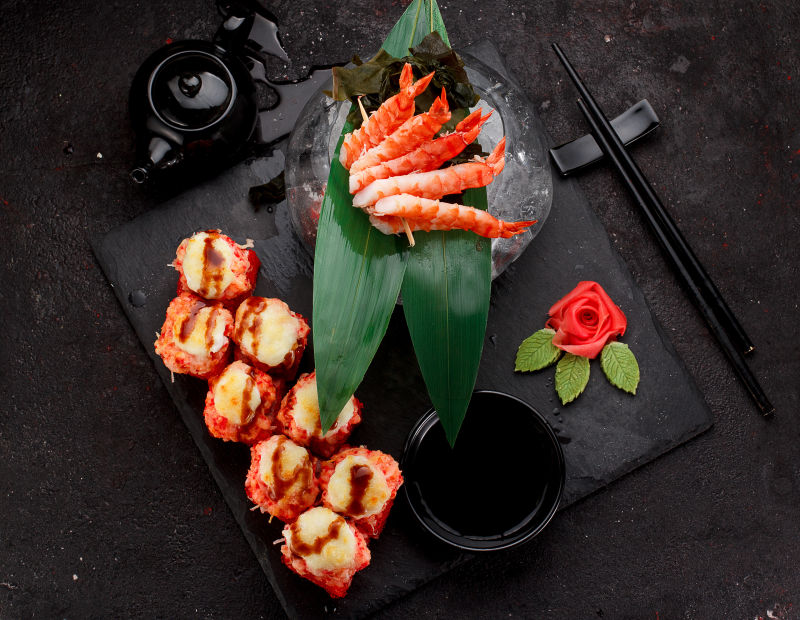 日本料理寿司卷和虾串在石板上的黑色混凝土背景