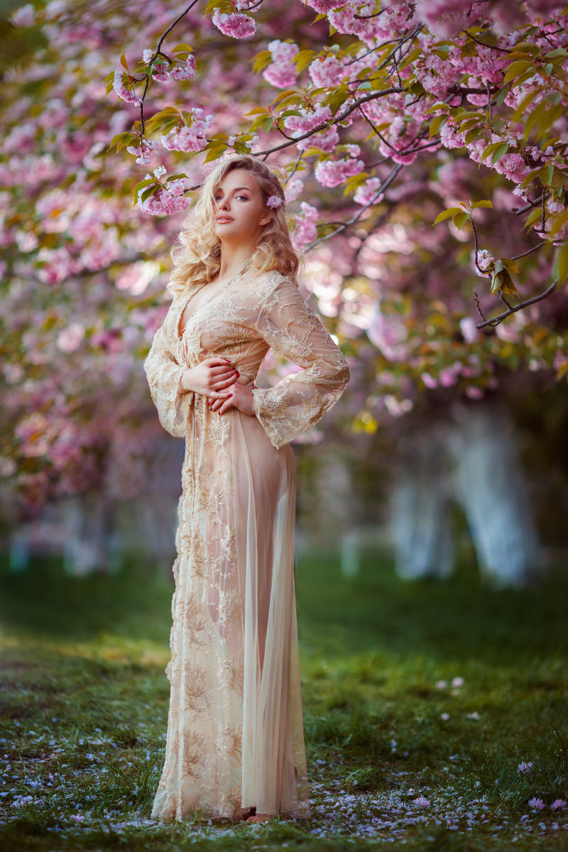 性感的年轻女子站在美丽的花朵下