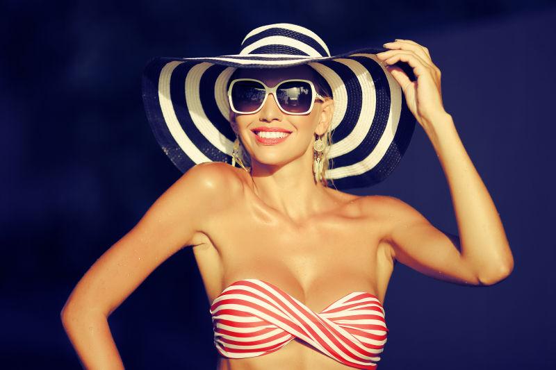 戴帽子和太阳镜的快乐年轻女子