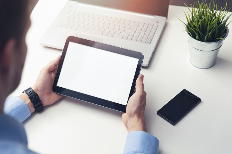 在办公桌上手持空白数字平板电脑的商人