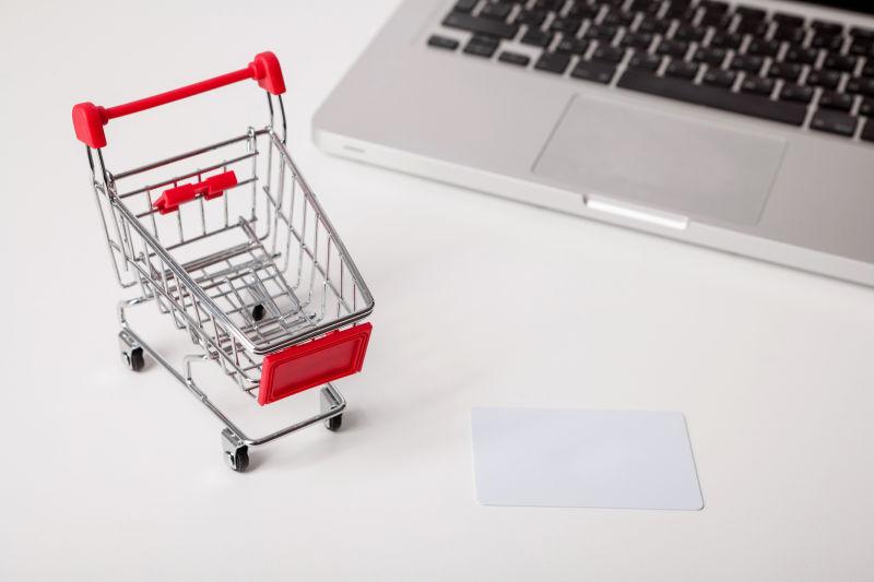 银行卡附近的笔记本电脑和迷你购物车