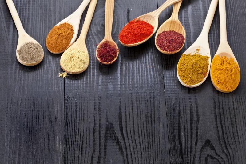 木质背景上的木勺子与香料