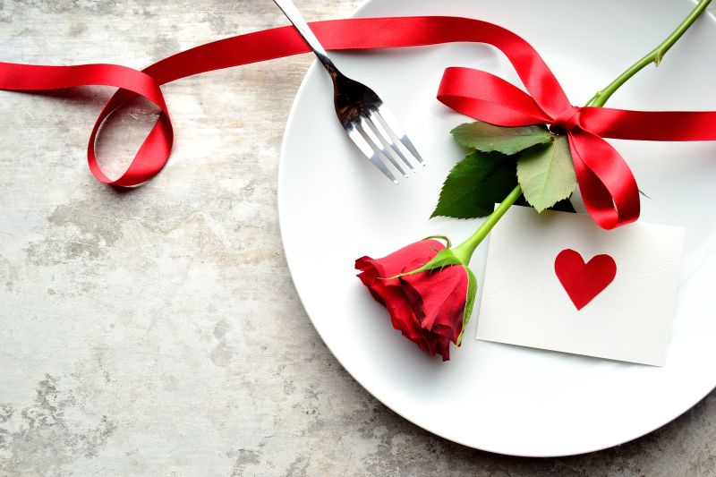 白色盘子上的用丝带绑住的红玫瑰