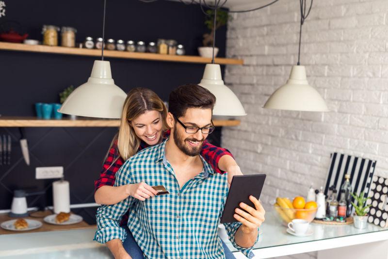 一张持有信用卡和网上购物的快乐情侣