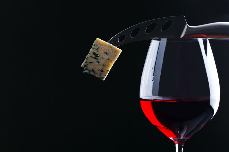 红酒与用刀戳着的奶酪块