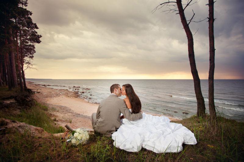 海边亲吻的新婚夫妇