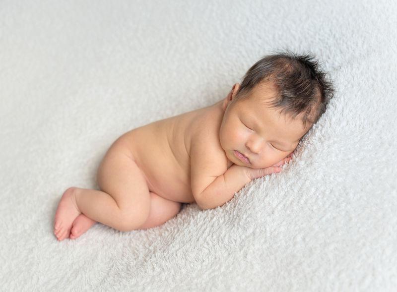 趴在白色毯子上睡觉的小婴儿
