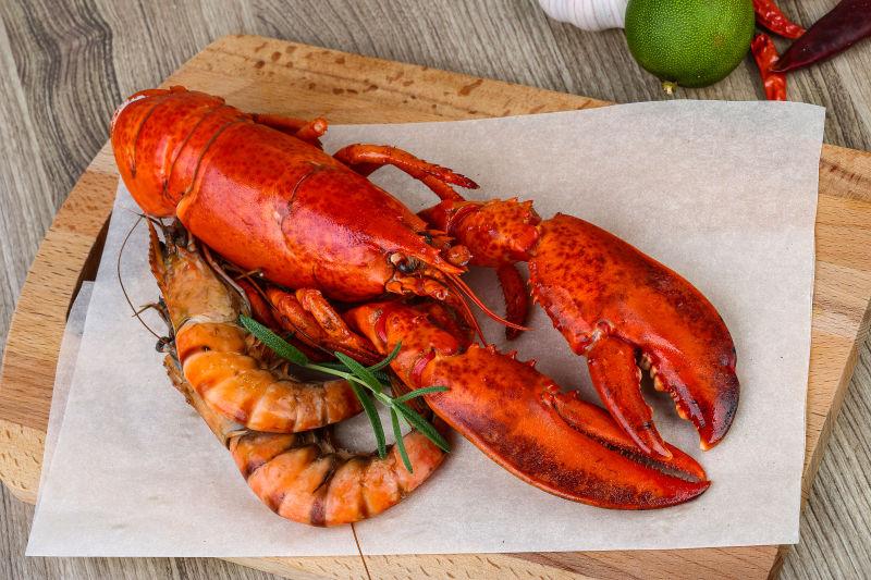 木砧板上的防油纸上的红色的龙虾和普通虾