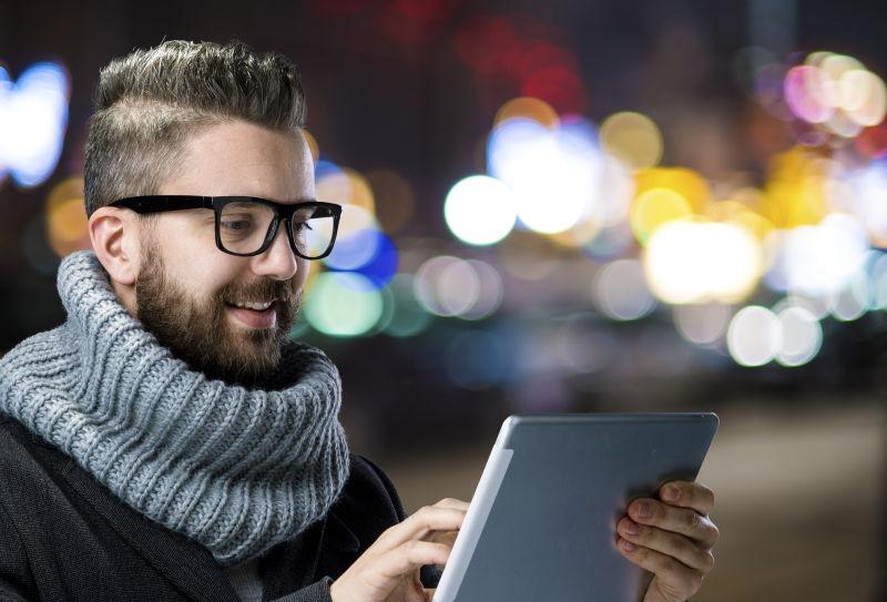 街道上玩着平板的时尚男人