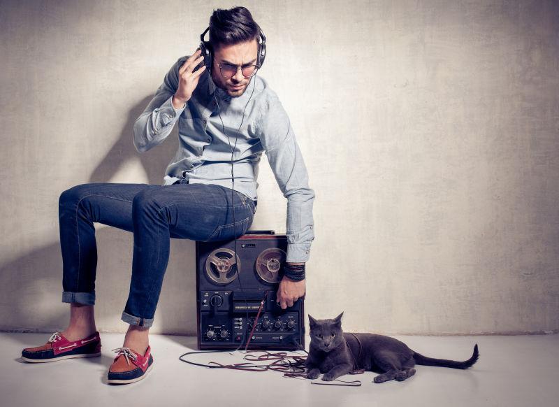 英俊的男人和猫在磁石电话上听音乐