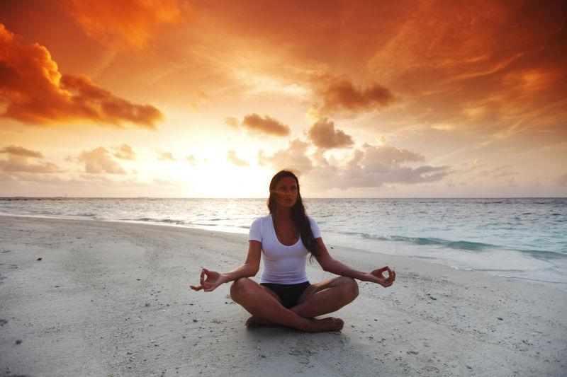 在黄昏的海滩上练习瑜伽的美女