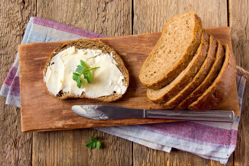 欧式木制背景上的用黄油和欧芹涂抹的面包