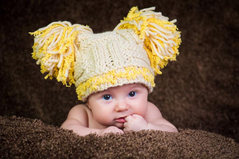 可爱的新生儿的针织冬帽米色背景