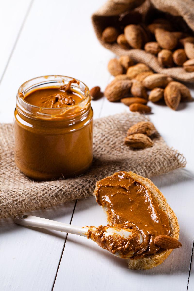 杏仁酱在一个玻璃罐和一个陶瓷勺