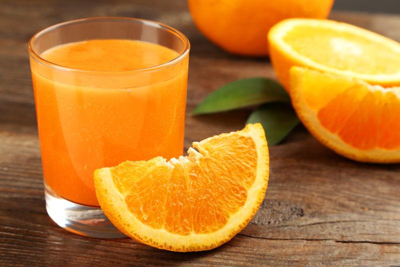 橙色水果和棕色玻璃背景的果汁玻璃