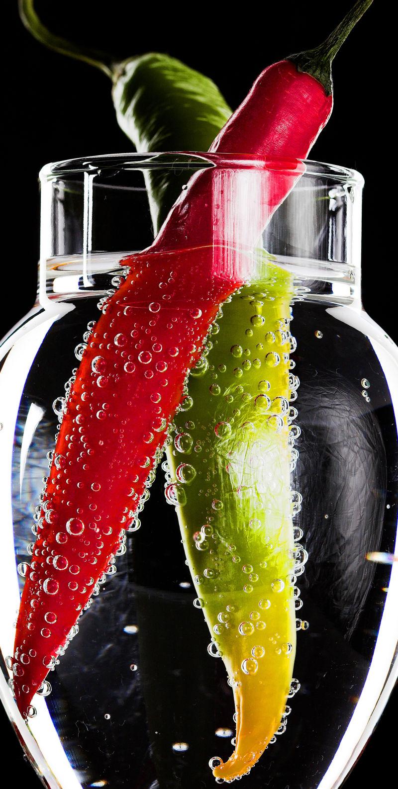 黑色背景下泡在水里的辣椒