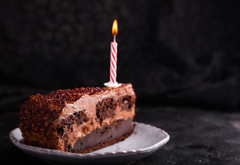 黑色背景下一块巧克力蛋糕上的蜡烛