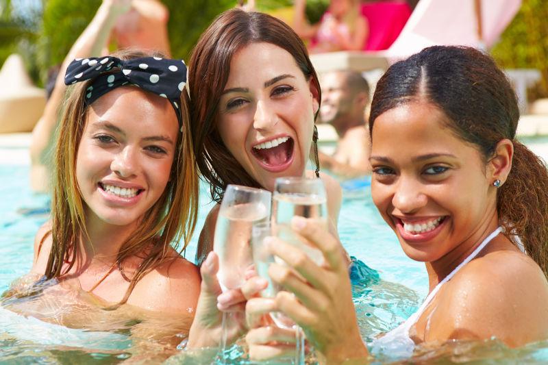 在游泳池里和香槟的三个女人