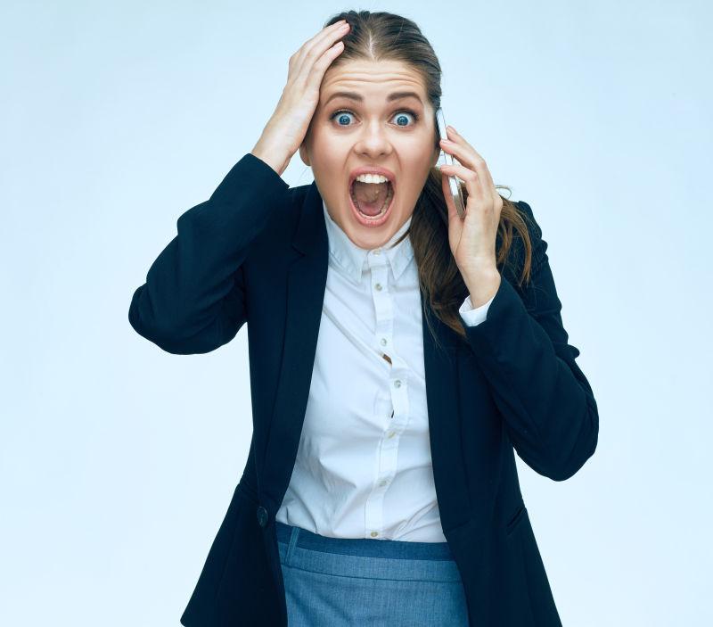 一脸吃惊的打着电话的女商人