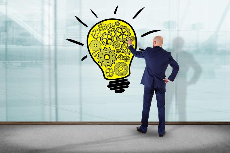 一位商人在墙前画灯泡灯创意