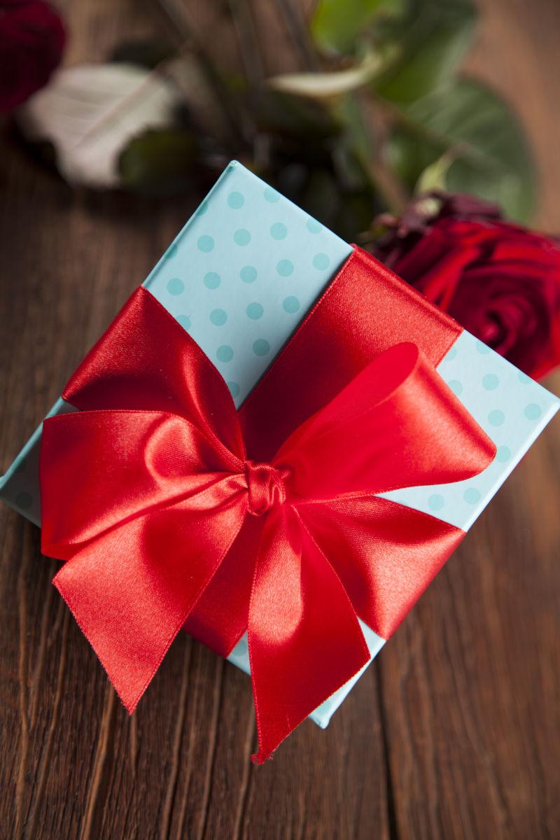 木桌背景前的情人节红玫瑰与礼品盒