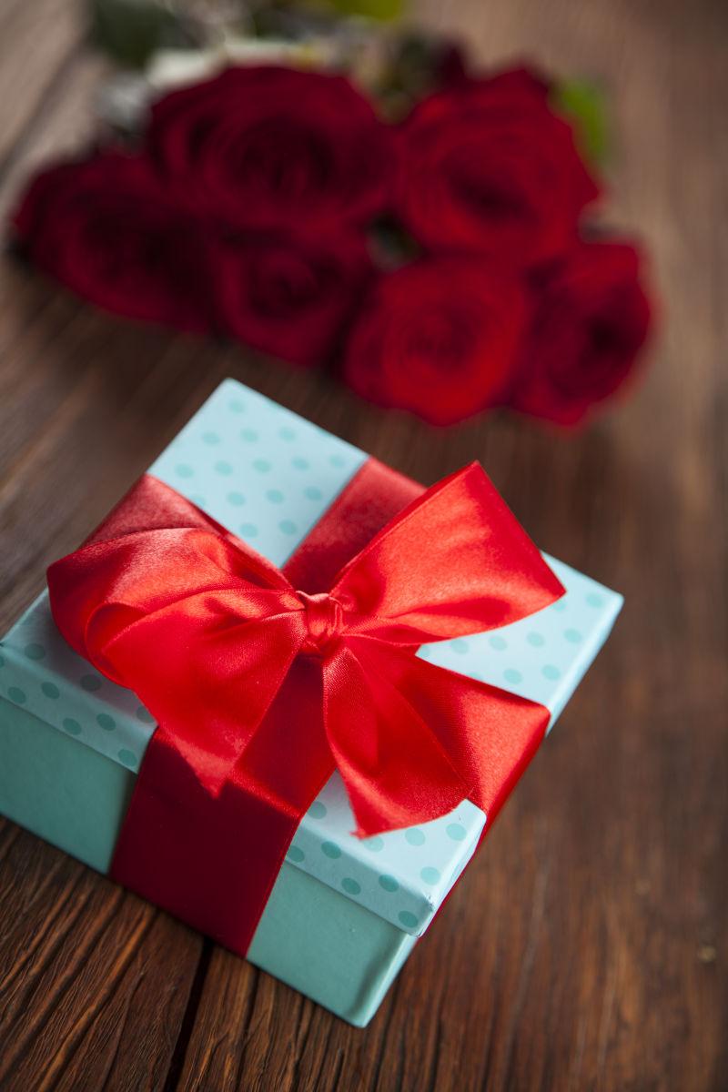 木桌上的红玫瑰和礼品盒