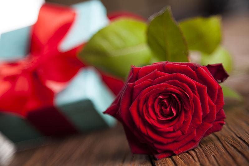 木桌上礼品盒背景前的玫瑰花