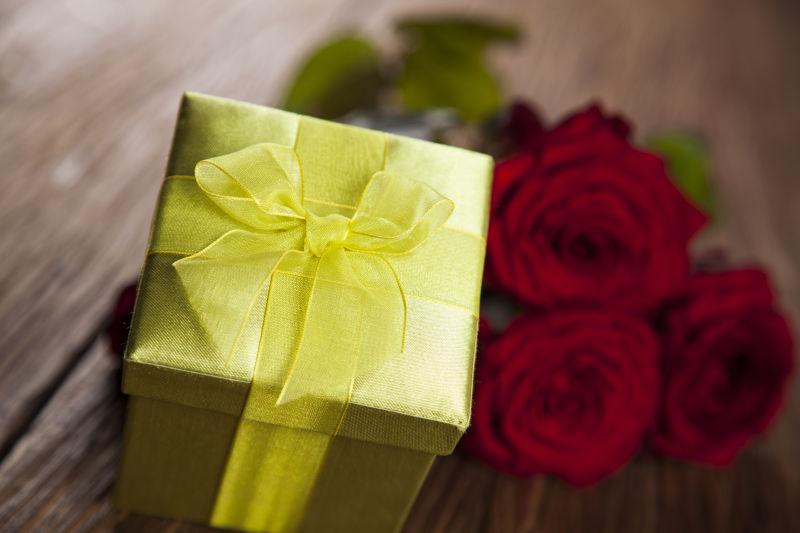 红玫瑰和黄色礼品盒
