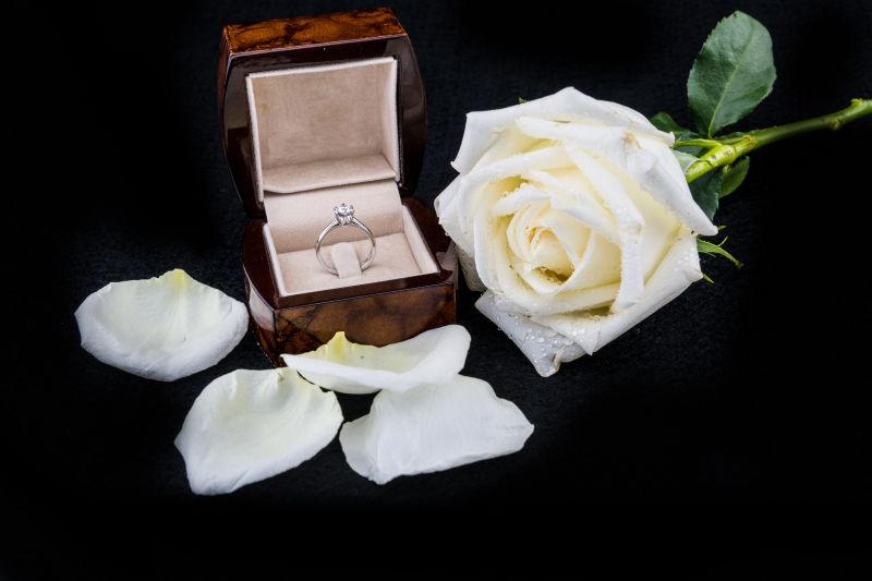 黑色背景上的白色玫瑰花和钻戒