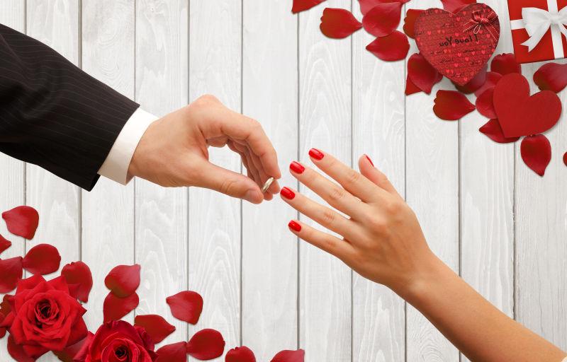 花瓣背景中男人把订婚戒指放在女人手上