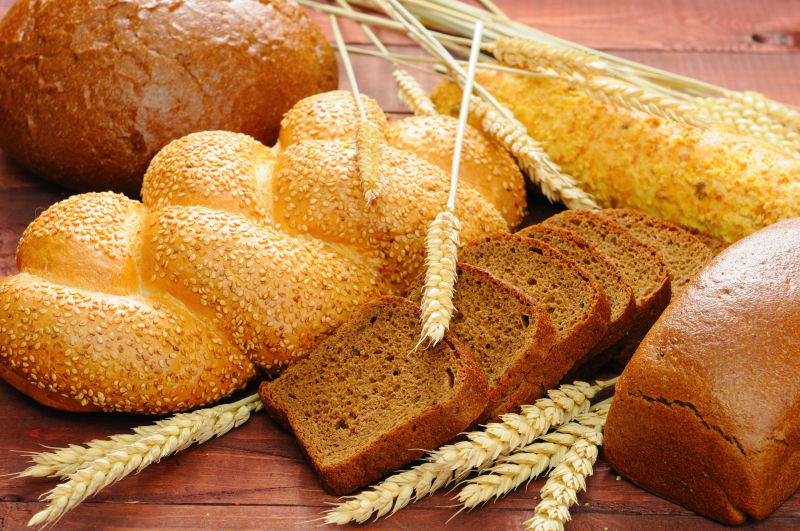 木桌上的切片面包与麦穗