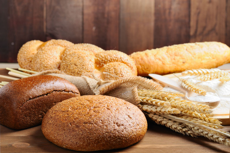 木桌上的金色传统面包与麦穗