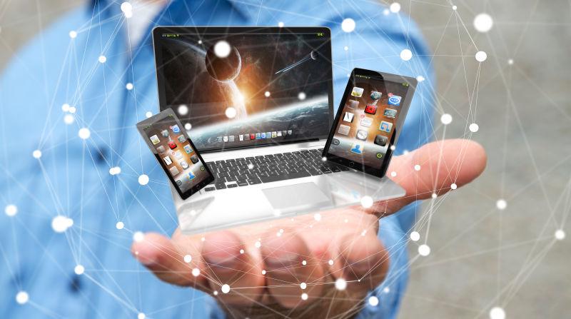 手掌上有笔记本电脑和平板电脑的商人