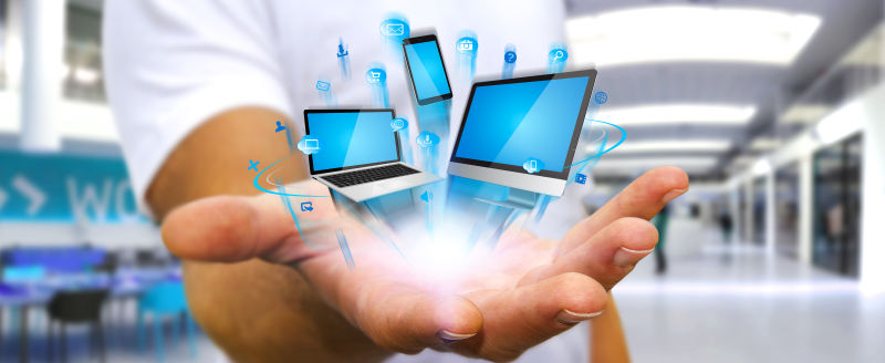 手里拿着科技设备电脑电话和平板电脑的人