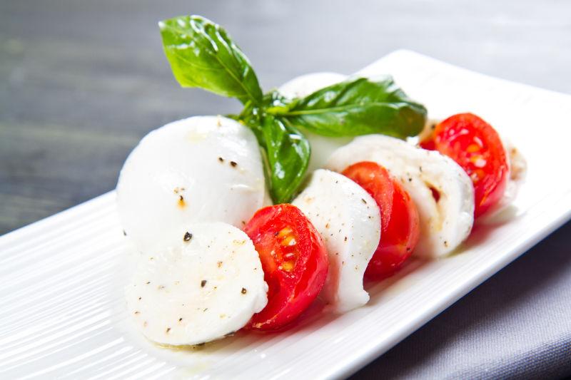 白色盘子里的西红柿和罗勒叶