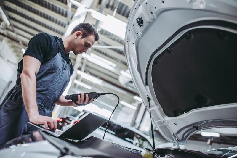 汽车修理厂里的手拿操作仪器的工人