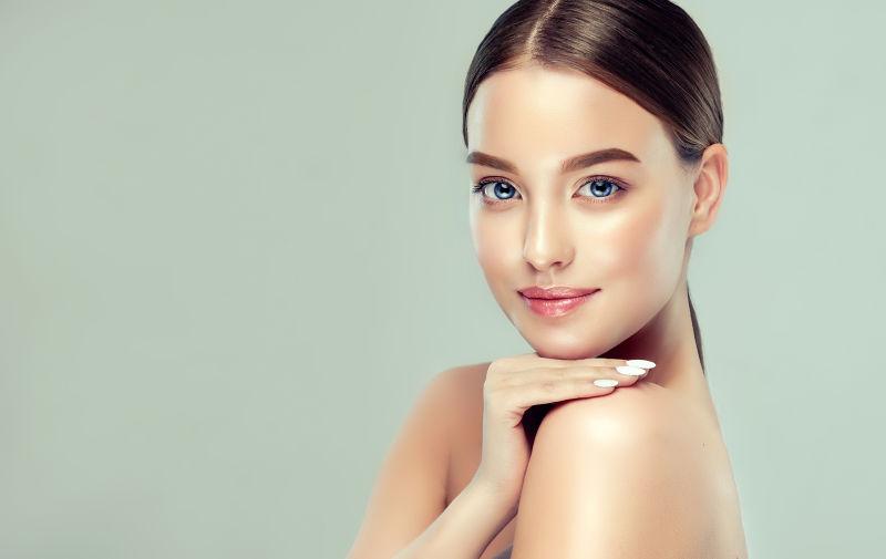 绿色背景下美丽的年轻女孩的皮肤护理