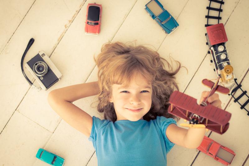 小女孩在家玩老式汽车玩具