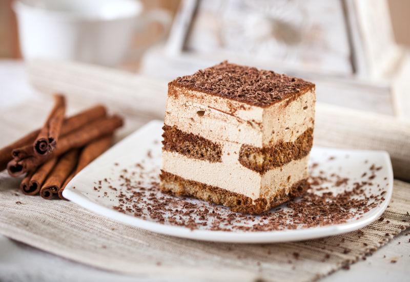 木桌上的提拉米苏甜点蛋糕和肉桂棒