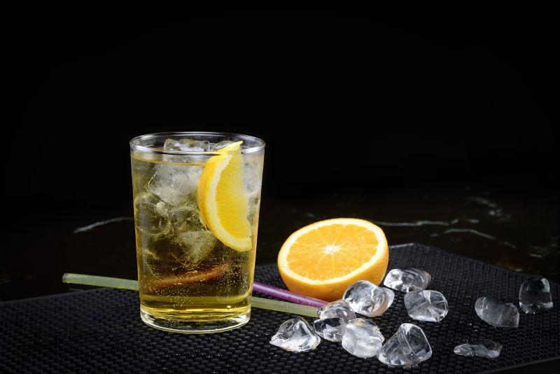 黑色背景上的放着柑橘的鸡尾酒杯