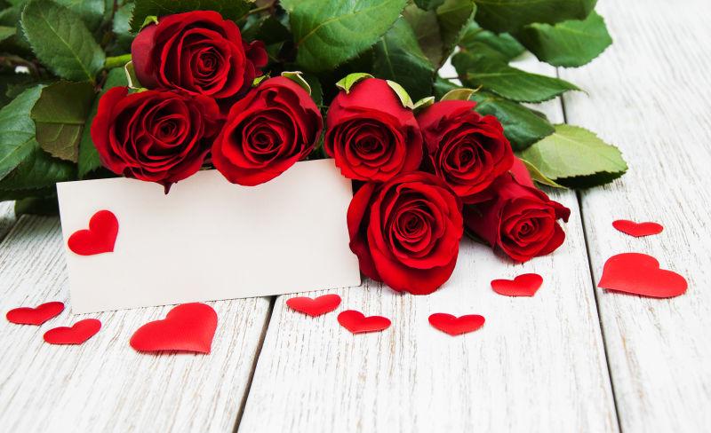 木桌上的红玫瑰和情人节贺卡