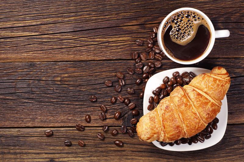 木桌上的羊角包咖啡与咖啡豆