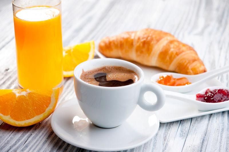 木桌上的咖啡和橙汁面包等早餐