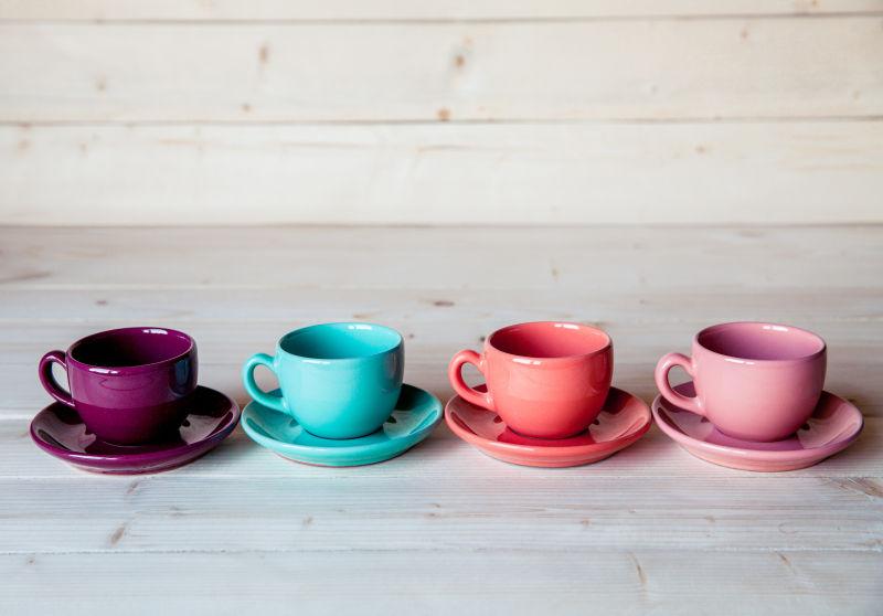 木桌上的四个彩色咖啡杯